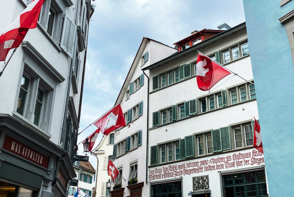 Old city centre of Swiss town Zurich. View of a street with Swiss flags placed on the traditional buildings.